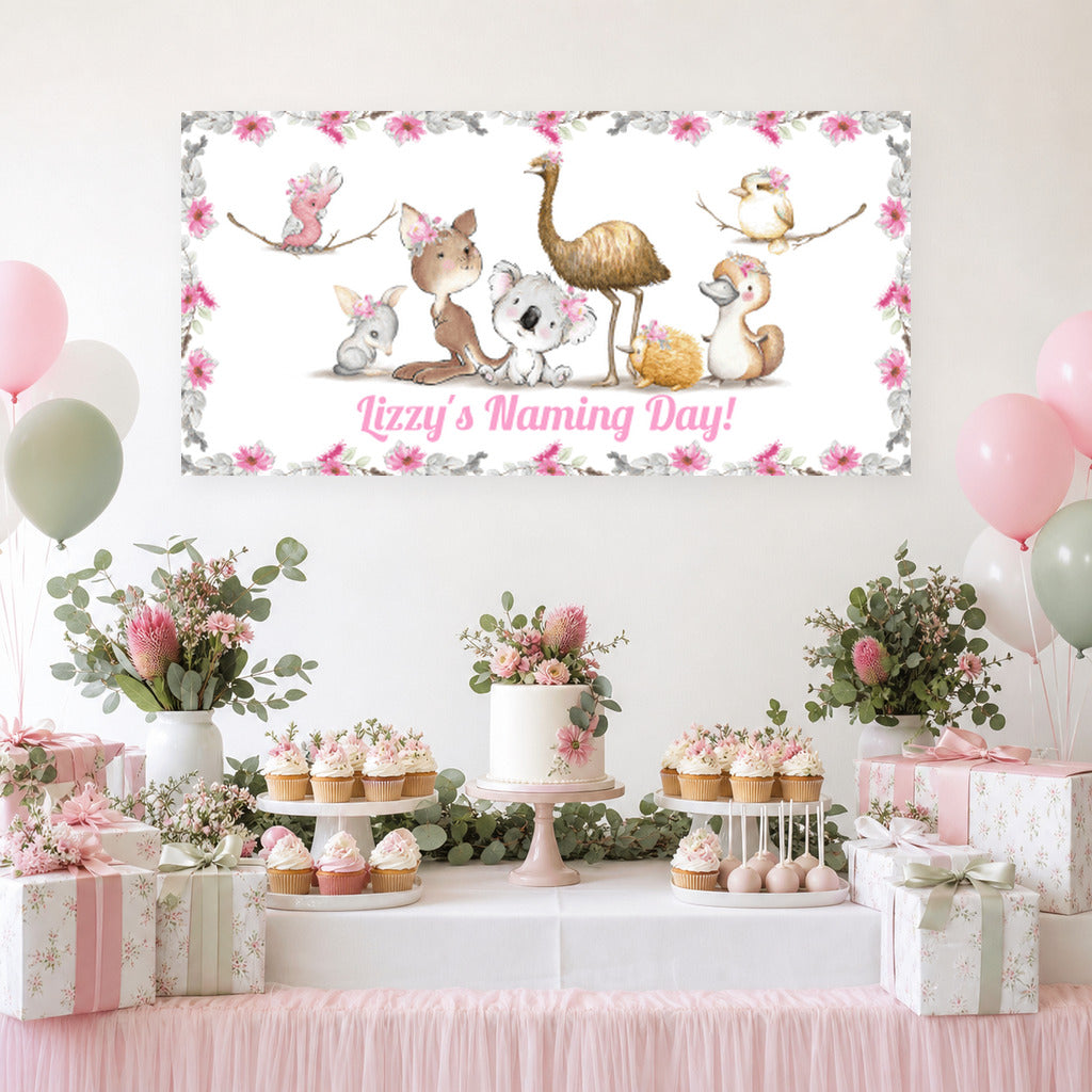 Floral Australian animals naming day dessert table with Izzy's personalised banner, cake, pink balloons and native floral decorations.