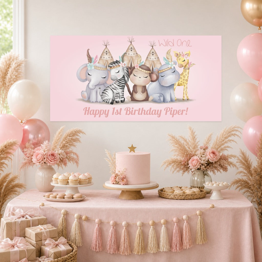 Girls Boho Jungle Wild One first birthday decorations with Piper's original personalised animal banner, a blush pink cake, cupcakes, balloons and dried flowers.