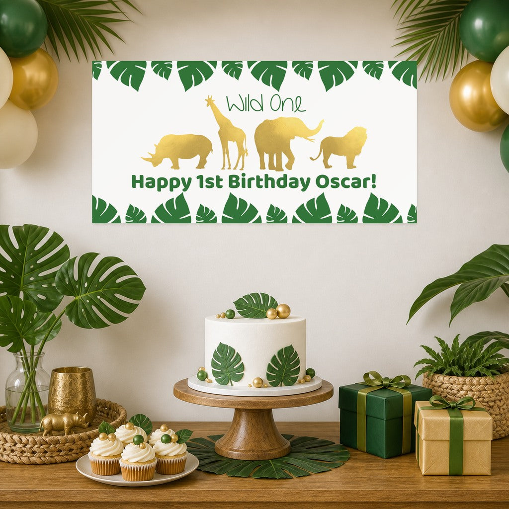 Gold Safari Wild One first birthday decorations with Oscar's original personalised animal banner, a leaf-decorated cake, cupcakes, green and gold balloons and matching gifts.