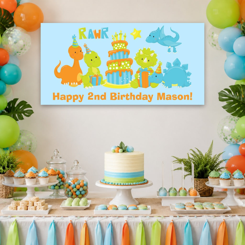 Little boys dinosaur birthday dessert table with Mason's personalised blue banner, dinosaur cake, orange and green balloons and matching decorations.