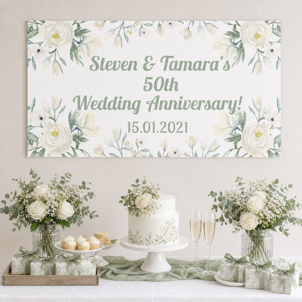 White Floral Wedding Anniversary Decorations with a personalised banner, coordinated cake, white roses and sage foliage.