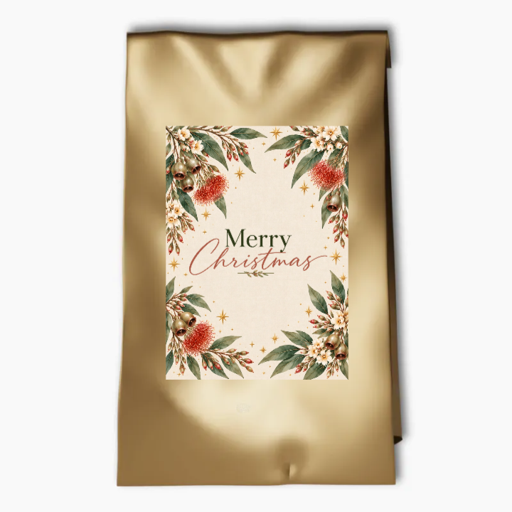 Aussie Botanicals Christmas party bag label with Merry Christmas lettering, eucalyptus, native flowers, festive baubles and gold stars on cream.