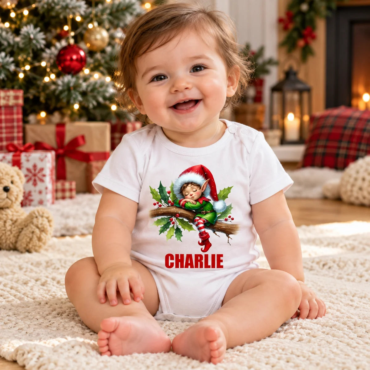 Baby wearing a personalised white Christmas baby romper with CHARLIE artwork.