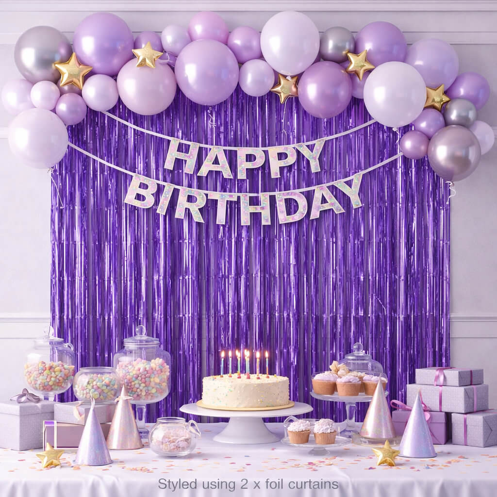 Purple foil fringe curtain party backdrop with balloons and cake table styling