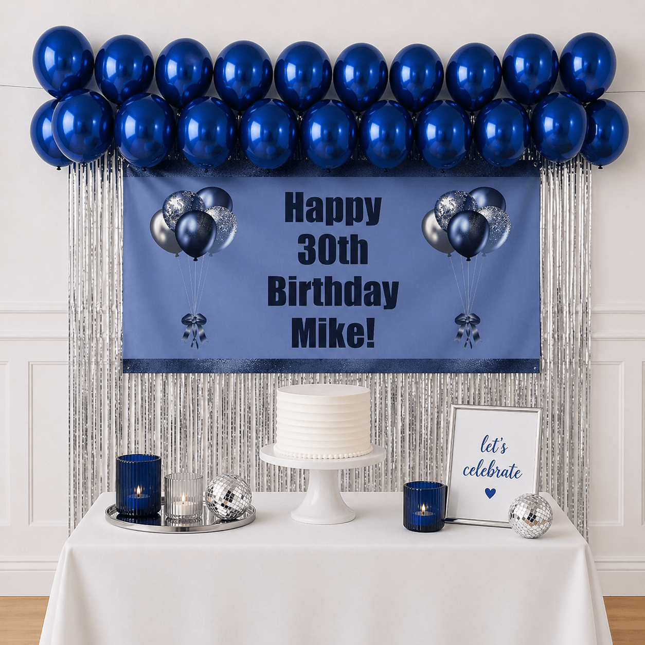 Personalised navy blue celebration party package with custom text banner, sapphire blue balloons and silver foil fringe curtains displayed as a completed party setup