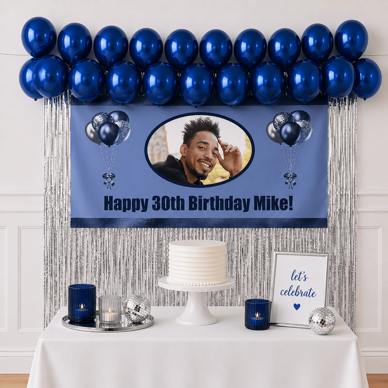 Personalised navy blue celebration party package with photo banner, sapphire blue balloons and silver foil fringe curtains displayed as a completed party setup