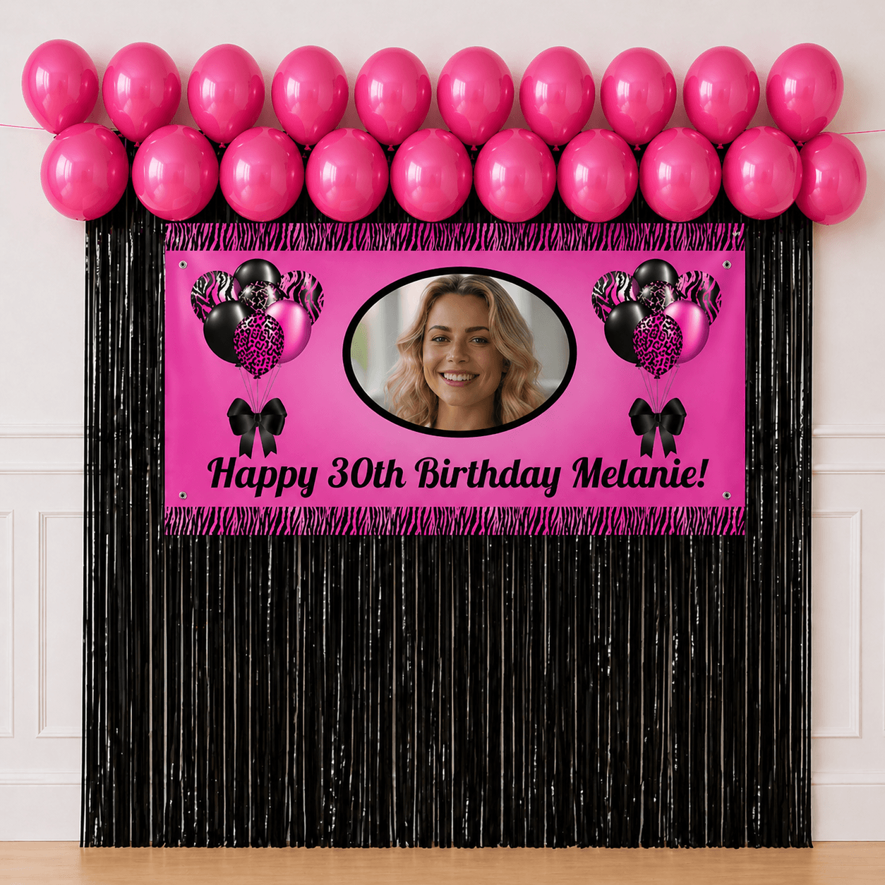 Personalised pink and black celebration party package with photo banner, hot pink balloons and black foil fringe curtains displayed as a completed party setup