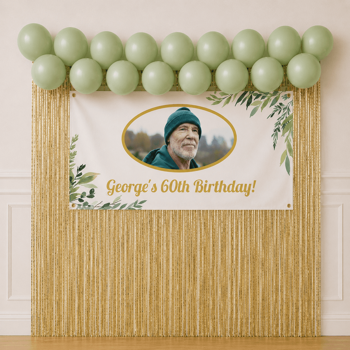 Elegant eucalyptus birthday party setup with personalised photo banner, sage green balloons, gold foil backdrop and cake table styling